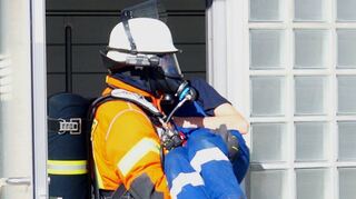 Ein Feuerwehrmann rettet eine Verletzte Person aus dem Gebäude.