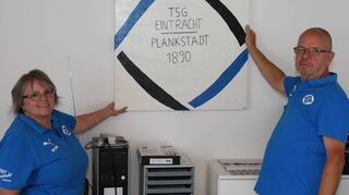 Die Vorstandsmitglieder Monika Hönig und Herbert Mölleken zeigen, wo eines der Gemälde der Tischtennisspielerin Sarah Veith aufgehängt werden soll.
