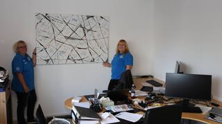 Sandra Schöffmann (l.) und Marion Brazel halten ein weiteres Veith-Werk im Konferenzraum probeweise an die noch kahle Wand.