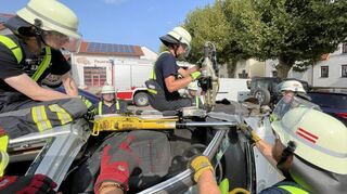 Die Feuerwehrmänner schaffen gemeinsam bei der Übung eine große Öffnung für den Zugriff des Rettungsdienstes bei einem Fahrzeug in Seitenlage.