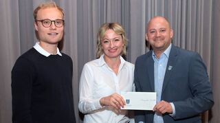 Kerstin Schaub (Abteilungsleiterin Leichtathletik) erhält von Pascal Seidel die „Ehrengabe“ der Gemeinde Oftersheim – links: Moderator Jakob Gieser.