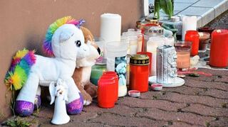 Plüschtiere und Kerzen stehen nach der Tat am Hauseingang zum Tatort in Hockenheim.