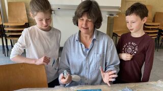 Die Leiterin der Jugendkunstschule Andrea Tewes zeigt den Geschwistern Magdalena und Jonathan, wie ihr Bild noch weiter bearbeitet werden kann.