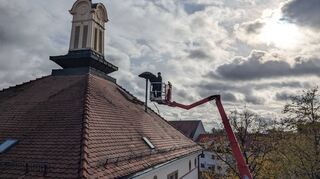Die drei alten Sirenen auf den Dächern des Rathauses, der Schule und eines Mehrfamilienhauses in der Parkstraße haben ausge-dient und werden demontiert. Mit Hilfe eines Hubsteigers wird der Wechsel auf dem Dach des Rathauses vollzogen.