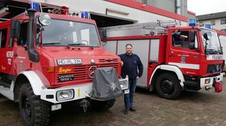 Kommandant Sven Schmitt zwischen den beiden „Oldtimern“, die durch die Neuanschaffung frühestens 2026 ersetzt werden sollen: Links das knapp 40 Jahre alte Löschgruppenfahrzeug, rechts der rund 27 Jahre alte Rüstwagen.