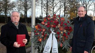 Bei der Gedenkfeier zum Volkstrauertag auf dem Friedhof legen Pfarrer Erwin Bertsch (l.) und Bürgermeister Dr. Ralf Göck einen Kranz nieder.