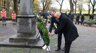 Pascal Seidel, Bürgermeister von Oftersheim, und Michael Barth-Rabbel, Diakon der Katholischen Kirchengemeinde Oftersheim, legen zum Gedenken an den Volkstrauertag einen Kranz nieder.