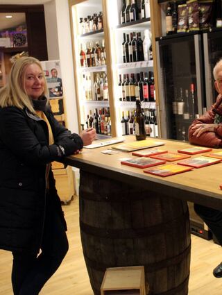 Umgeben von leckerem Wein und Hochprozentigem: Künstler Florian T. Franke von Krogh mit seinen Werken und Besucherin Evelyn Tedesco bei „Falke exklusiv“.