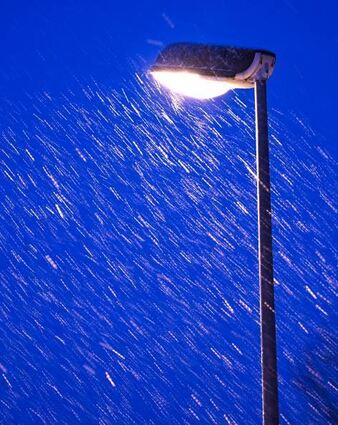 Eine Straßenlaterne bei Schneegestöber in der Nacht.
