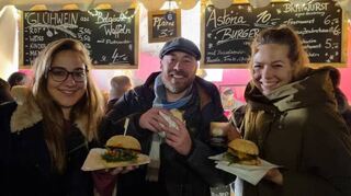 Amelie, Nico und Julia probieren Straußenburger (10 Euro) und Wildschweinbratwurst (5 Euro) am Stand vom Straußenhof Walldorf. Die selbst hergestellten Spezialitäten haben viele Fans auf dem Weihnachtsmarkt Schwetzingen, wie auch die Warteschlange am Donnerstagabend zeigt.