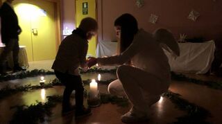 Engel Amelie (14) hilft Kindern, den Raum mit Kerzen zu erhellen.