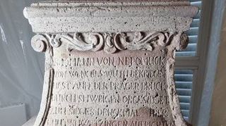 Der Diplom-Restaurator hat die Inschrift des Sockels auf ein Blatt Papier übertragen. Das Denkmal des Nepomuk wurde 1751 fertiggestellt und von den Bürgern initiiert.
