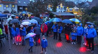 Zur Eröffnung des Weihnachtsmarkts in Plankstadt kommen trotz Regen viele Besucher. Neu ist in diesem Jahr neben dem Pfandsystem der Standort: Wegen der Baustelle findet der Markt vor der evangelischen Kirche statt.