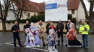 Ein erster Kick-off für die Umsetzung des Projekts Rothacker’sches Haus: Symbolisch mit Werkzeugen ausstaffiert und im erlauchten Kreis bekannter Persönlichkeiten wie Kurfürst Carl Theodor, Kurfürstin Elisabeth Auguste und dem kleinen Wolfgang Amadeus Mozart stehen Museums- und Projektleiter Lars Maurer (v. l.), Franz Boxheimer (Bauamt), Marc Sommer (Vertreter Architekten), Andreas Rettig (Rechnungsprüfungsamt), Kulturreferentin und Projektleiter Dr. Barbara Gilsdorf, Grafikdesigner Klaus-Peter Deimann, Künstler und Tätowierer Dominik Göhlich sowie Bauamtsleiter Joachim Aurisch vor der am Dienstag aufgestellten Bauprojekttafel am Alten Messplatz.
