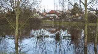 Blick auf die Gemeinde von östlich der verlängerten Rheinhäuser Straße: Der Kriegbach ist schon über seine Ufer getreten und staut sich zu einem See.