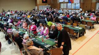 Die Senioren der Gemeinde freuen sich über viel Gemütlichkeit beim vorweihnachtlichen Zusammensein. Sie singen und lachen gemeinsam, während Kaffee und Kuchen gereicht werden.