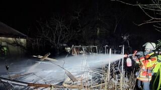 In der Gartenbauanlage werden die in Brand geratenen Holzbretter aus einem Gewächshaus gelöscht.