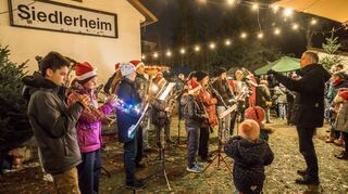 Der Musikverein unter der Leitung von Erik König begeistert auch die Besucher des Weihnachtsmarktes am Siedlerheim mit saisonal passenden Stücken.