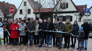 Das blau-weiße Band ist symbolisch durchtrennt: Vertreter von Gemeinderat, Verwaltung, am Bau beteiligten Firmen und Anwohner geben den neu gestalteten Platz am Dorfgemeinschaftshaus frei.