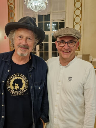 Musiker Wolfgang Niedecken im Bob-Dylan-Shirt und  OB René Pöltl mit Schiebermütze im Theaterfoyer im Schloss.