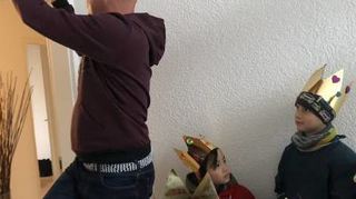 Landtagsvizepräsident Daniel Born klebt das Segensband selbst über seine Tür, da die Kinder zu klein dafür sind.