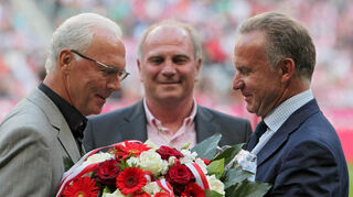 Fußball-Bundesliga 3. Spieltag am 11. September 2010 in der Allianz Arena in München. Der Ehrenpräsident des FC Bayern, Franz Beckenbauer (l.), erhält vom damaligen FC Bayern Vorstandsvorsitzenden Karl-Heinz Rummenigge einen Blumenstrauß. In der Mitte ist der ehemalige FC Bayern Präsidenten Uli Hoeneß zu erkennen.