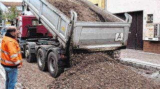 Lkw laden Material für den Belag der Heidelberger Straße ab, der in Schichten aufgetragen wird.