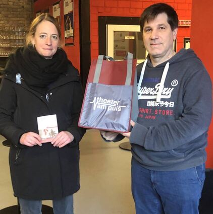 Theaterintendant Joerg Steve Mohr (r.) übergibt an Nadine Bikowski vom Diakonischen Werk symbolisch den „Sack mit Spendengeld“.
