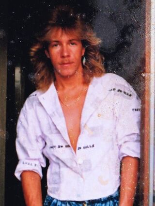 Die 1980er Jahre bestechen nicht nur durch ihre Musik, sondern auch durch ihre Mode. Welcher Musiker von „The News“ könnte das auf diesem Bild aus den 80ern sein – mit Frisur à la Bon Jovi, Federohrring und einer Bundfaltenjeans?