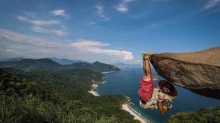 Bernardo hängt am Felsen „Pedra do Telegrafo“ mit dem Meer im Hintergrund. Touristen lassen sich hier in waghalsigen Posen ablichten.