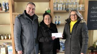 Vor erschreckend leeren Regalen übergeben Lothar Harant und Patrizia Knapp (r.) im Tafelladen einen kleinen Umschlag an Alisse Pljevljak.