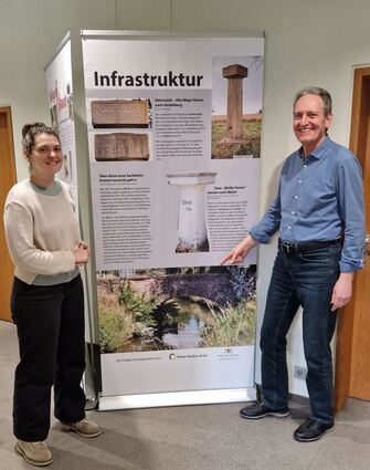 Katja Rheude vom Kulturamt der Gemeinde und Bürgermeister Dr. Ralf Göck ent-decken in der Ausstellung die Steinerne Brücke, die den Leimbach seit fast 250 Jahren überspannt.