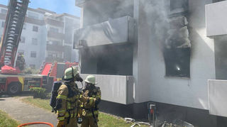 Trupps der Freiwilligen Feuerwehr sind im Juni 2023 unter Atemschutz beim Brand einer Wohnungen im Erdgeschoss des großen Hochhauskomplexes in der Bussardstraße in Rohrhof im Einsatz.