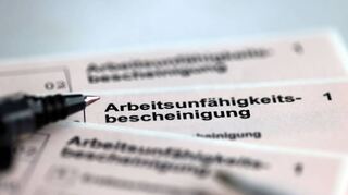 Stifte liegen auf den Arbeitsunfähigkeitsbescheinigungen, die Arbeitnehmer im Falle einer Krankschreibung erhalten.