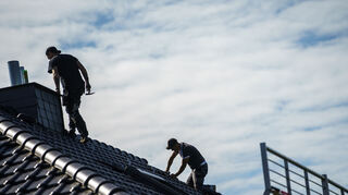 Arbeiter bereiten das Dach für die Montage von Solarpanels vor. Photovoltaik wandelt Sonnenlicht in Strom um. Davon lässt sich ein großer Teil für Geräte zu Hause sowie für Heizungen und Elektroautos nutzen.