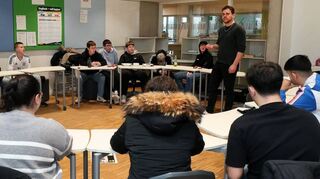 Noah Eschwey (stehend) aus der Zeitungsredaktion ist hier im Gespräch mit einer Gruppe der Klassen 7 bis 10.