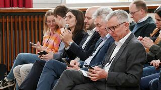 „KI meets Europawahl“ heißt es in der Aula der Ehrhart-Schott-Schule. Die Gäste nehmen an einer Live-Abstimmung teil.