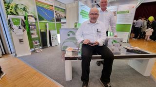 Udo Bellmann (sitzend) und Heiko Lauer von der AVR Energie GmbH stellen eine Solarbank vor ("i-bench plank"), auf der man nicht nur sitzen, sondern auch gleich sein Handy aufladen kann - entweder kabellos oder mit Kabel. Solche Bänke stehen bereits im öffentlichen Raum, etwa in Bammental und Pforzheim.