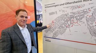 Patrick Körner von der Geschäftsführung der Stadtwerke Schwetzingen zeigt den Fernwärmenetzausbau in Schwetzingen und den umliegenden Gemeinden. Am Stand der Stadtwerke hängen aktuelle Pläne, auf denen das bisherige Leitungsnetz zu sehen ist.