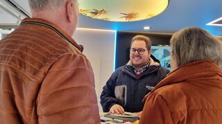 Denis Müller, Geschäftsführer der Firma Ciling aus Oftersheim berät in Sachen Infrarotheizlösungen. Über ihm ist ein Infrarotdeckenmodul - wärmend unter Palmen, da kommt am stürmischen Samstag bei der Energie-Messe Rhein-Neckar in Schwetzingen karibisches Flair auf.
