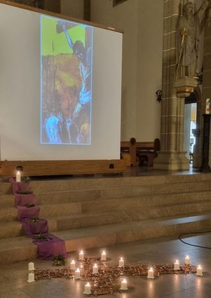 Viele kleine Weidekreuzchen bilden auf dem Kirchenboden ein großes Kreuz. Die Kerzen stehen für die Kreuzwegstationen.