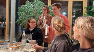 Pfarrerin Katharina Treptow-Garben und Vikarin Johanna Falkenhahn, hinter ihr stehend, beim Tischabendmahl.