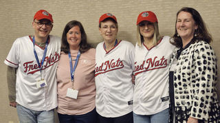 Frisch eingekleidet mit Trikots des Baseball-Teams Fred Nats, das in der zweiten Liga spielt: OB Dr. René Pöltl (v. l.), Brenda Martin, Stefanie Pöltl, Sabrina Cass und Fredericksburgs Bürgermeisterin Kerry Devine.