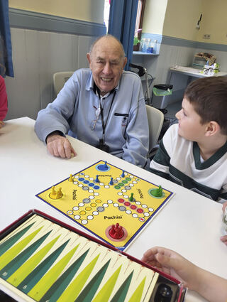 Der Senior Karl-Heinz Fütterer genießt bei einer Partie „Mensch ärgere dich nicht“ die Zeit mit dem Hortkind Tobias.