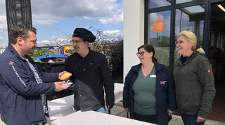 Manuel Wamser (v. l.) vom DRK, zuständig für die Tafelläden in der Region, nimmt von Gastronom Sandro Camilleri eine Currywurst in Empfang. Die Leiterin des Tafelladens Hockenheim, Tanja Reinhard, und Camilleris Helferin Bärbel Hesping unterstützen den Gastronom hinter der Theke.