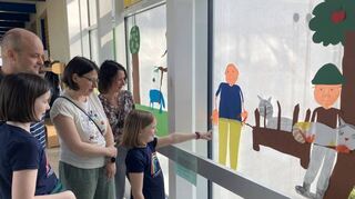 Die achtjährige Charlotte erklärt ihrer Familie die Fensterbilder zur Geschichte „Peter und der Wolf“, die sie während der Projekttage mitgestaltet hat.