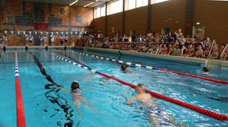Die Mitschüler feuern die Schwimmer an. Auf Wunsch begleitet ein Erwachsener die Kinder im Wasser, sodass auch weniger sichere Schüler teilnehmen können.