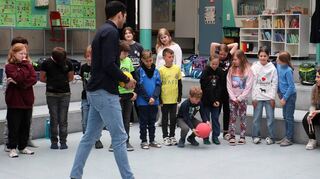 Kürsat Özdemir (v.) und Rauan Mardnli (5. v. r.) üben mit Kindern, die sich mit geschlossenen Augen einen Ball, in dem ein Glöckchen ist, auf Zuruf zuspielen sollen.