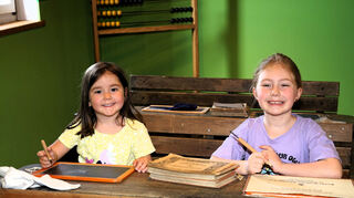 Hannah (4) und Luisa (7) besuchen den alten Klassenraum mit Schiefertafel.