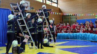 Die „Feuerwehrleute“ der Jahnschule balancieren bei der Aufführung zu den Projekt-tagen in ihren Uniformen gekonnt auf ihren Leitern.